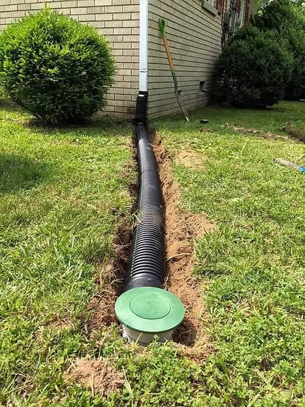 Downspout tied into a buried drain line carrying roof runoff away from a Memphis foundation